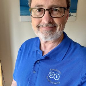 An image of Richard Swainson. He is smiling, wearing glasses and in a blue polo t-shirt with the Swainson Productions logo on the crest.